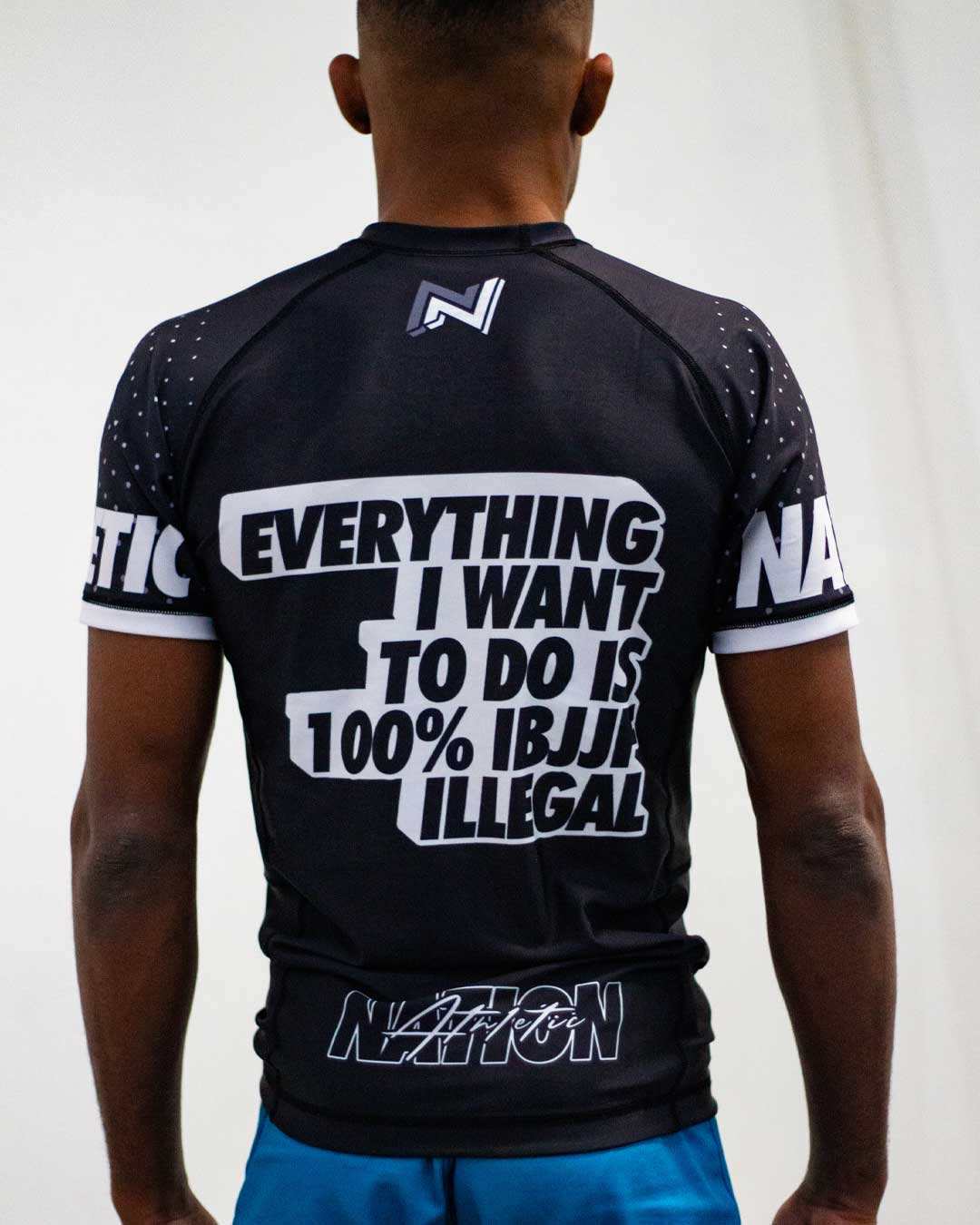 Back view of a model wearing a Nation Athletic IBJJF white Ranked Rash Guard – Short Sleeve, compression fit BJJ competition rash guard