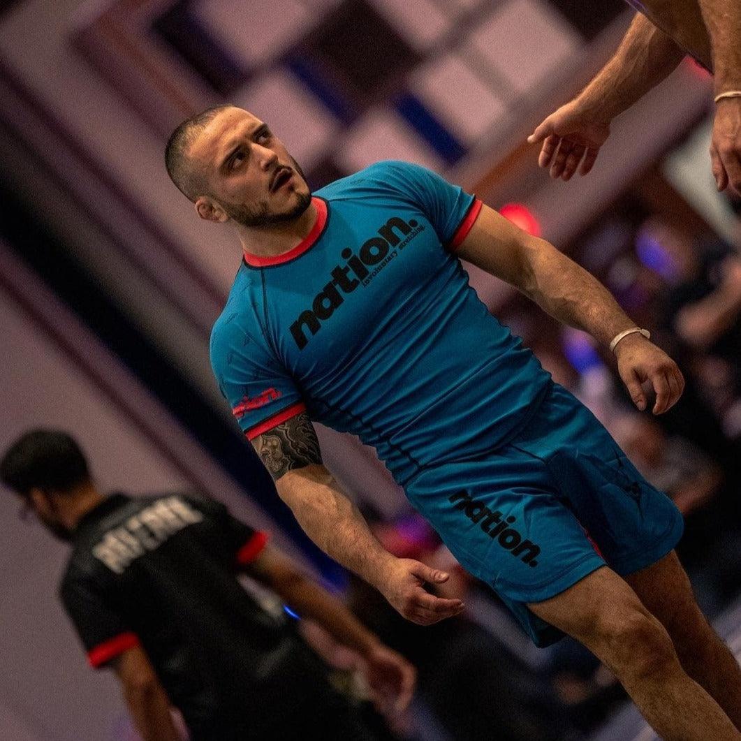 Front view of a competitor wearing Nation Athletic’s Murder Yoga Blue BJJ set rash guard and Shorts – durable No-Gi grappling shorts for Jiu Jitsu and MMA